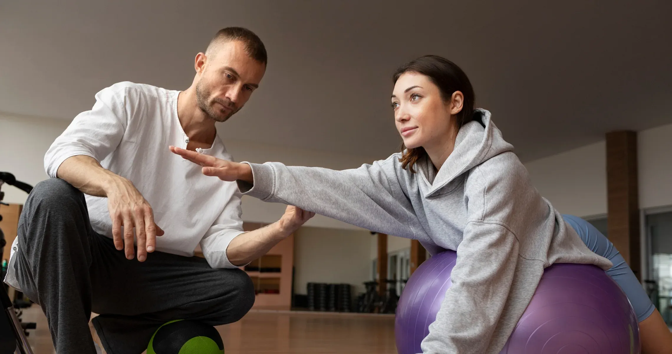 A patient using rehabilitation equipment with a therapist nearby